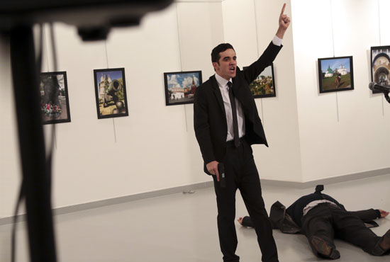 An unnamed gunman shouts after shooting the Russian Ambassador to Turkey, Andrei Karlov, at a photo gallery in Ankara, Turkey, Monday, Dec. 19, 2016. A Russian official says that the country's ambassador to Turkey has died after being shot by a gunman in Ankara. (AP Photo/Burhan Ozbilici)